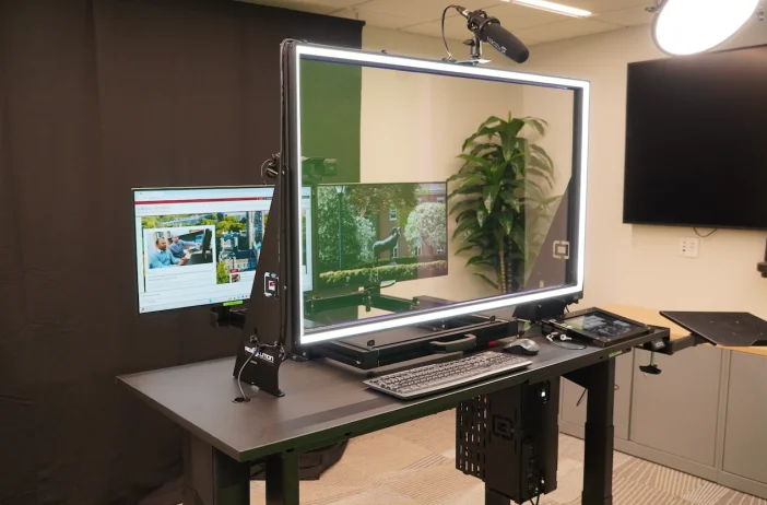 Desk-sized lit glass lightboard with microphone, monitor, keyboard and tablet in an office room.